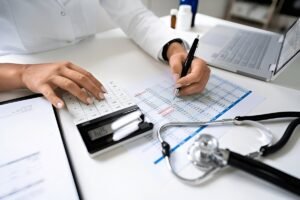Billing specialist reviewing a claims spreadsheet with a calculator and stethoscope on the desk